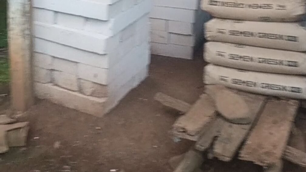 Tumpukan batako putih tersusun rapi di area pembangunan RTLH, dengan beberapa karung semen yang sudah membatu dan papan kayu yang sudah rusak dimakan rayap di sisi kanan di atas lantai tanah rumah penerima RTLH desa Cabak Kecamatan Tlogowungu Kabupaten Pati